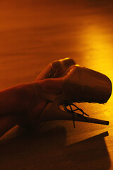 Close-up of pole dance platform heels on studio floor with dramatic warm lighting