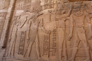 Ancient Egyptian wall relief with carved figures and hieroglyphs in stone