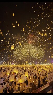 Spectacular night view of thousands of floating lanterns released into the sky with grand fireworks display during Yi Peng festival celebration