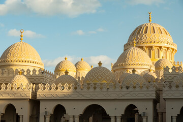 Golden domes of a building Mosque El Mina Masjid in Hurghada under a blue sky in a vibrant city during the late afternoon