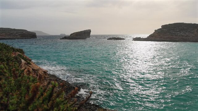 Malta Blue Lagoon landscape. Stunning view of the Blue Lagoon in Comino, Malta, showing the famous turquoise crystal clear waters and the rocky islet of Cominotto under a cloudy sky. 4k video