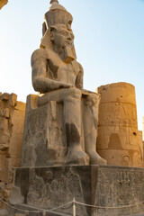 Large seated statue of an ancient Egyptian king in a historic temple at Luxor during daylight