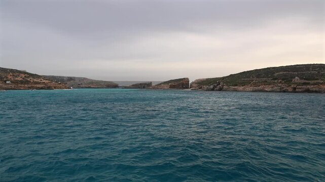 Malta Blue Lagoon landscape. Stunning view of the Blue Lagoon in Comino, Malta, showing the famous turquoise crystal clear waters and the rocky islet of Cominotto under a cloudy sky. 4k video