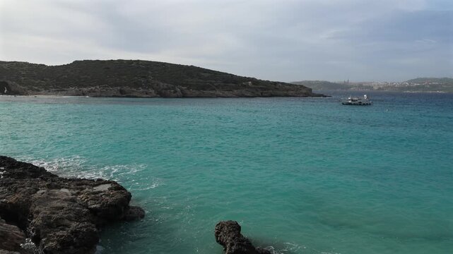 Malta Blue Lagoon landscape. Stunning view of the Blue Lagoon in Comino, Malta, showing the famous turquoise crystal clear waters and the rocky islet of Cominotto under a cloudy sky. 4k video