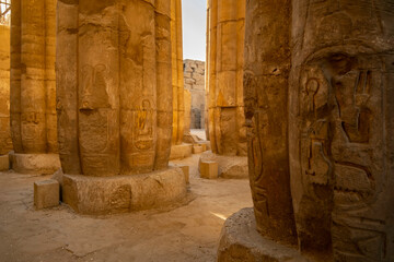 Ancient stone columns in a historic Luxor Temple with carvings in a warm evening light