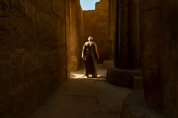 Man walks through ancient ruins in Luxor Temple Egypt under bright sunlight during late afternoon
