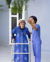 Happy senior woman enjoying gardening therapy with caregiver in nursing home backyard.