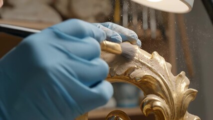 Person applying gold powder to ornate object