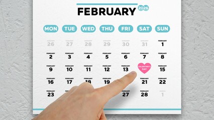 Close-up of a male hand pointing finger at the date of Valentine's Day 2026 on a wall calendar