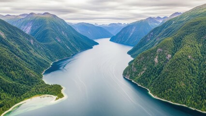Serene lake surrounded by lush green mountains under cloudy sky