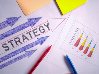 Business Strategy Concept with Directional Arrows with Rising Bar Graph, Pens and Financial Growth Chart