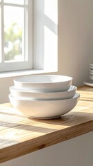 Stack Of Three White Ceramic Bowls On A Wooden Countertop Bathed In Soft Sunlight Near A Window