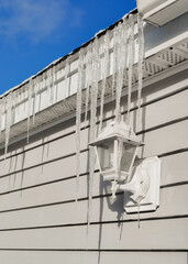 Icicles hanging from the edge of a house roof in winter.