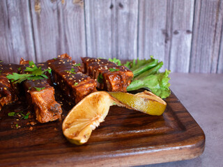 Plato de costillas de cerdo a la bbq con ajonjoli en una tabla de madera