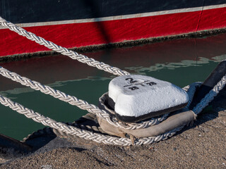 Mooring rope tied to a pier on the shore. Ship rope fastened to the dock in a mushroom shape