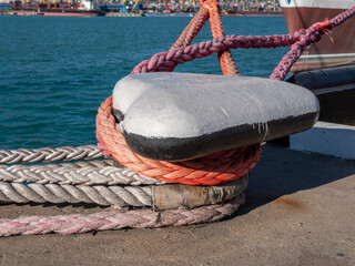 Mooring rope tied to a pier on the shore. Ship rope fastened to the dock in a mushroom shape