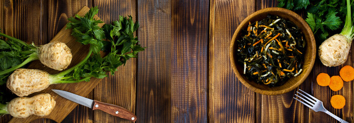Salad with seaweed, celery and carrots in the brown bowl on a  wooden background. Copy space. Top view.