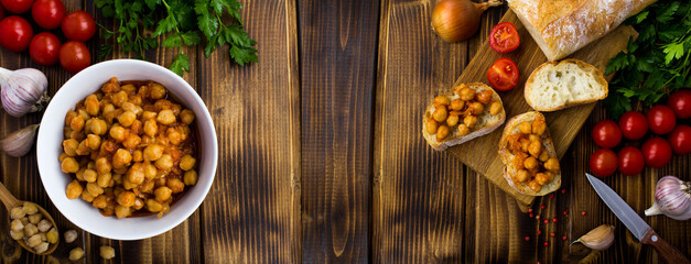 Chickpeas in the tomato sauce in the white bowl  and vegetarian sandwiches with chickpeas on a wooden  background. Top view.Copy space.