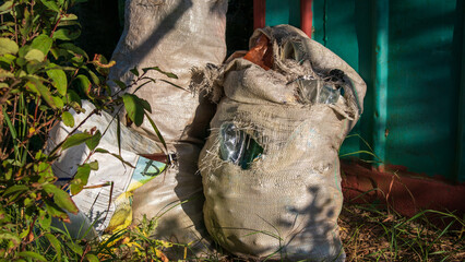 Two burlap sacks filled with collected waste sit outside