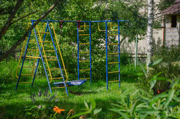 A children's iron playground in the garden. Stairs and a swing on the site for children