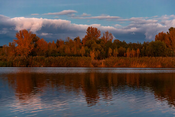 Dramatic storm front over fall shoreline and warm evening light