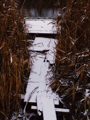 Atmospheric winter landscape with a broken bridge leading to dark water