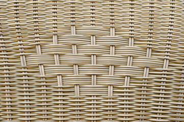 A close-up view shows the intricate details of a woven basket. The work highlights the pattern and texture formed by the woven strands.