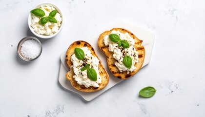 Delicious toast topped with creamy cheese, basil, and peppercorns, prepared on a white surface