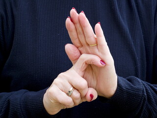 A pair of hands signing the consonant letter 'R' in British Sign Language.BSL.Communication.Hearing Impaired.