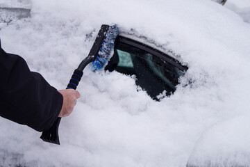 The driver is cleaning the car from heavy snow