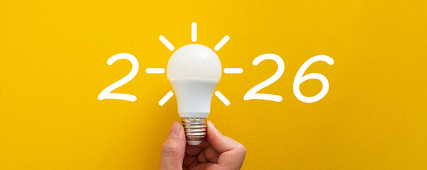 Hand holding lightbulb forming 2026 new idea concept