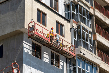 August 21, 2025: Construction lift with workers performing wall finishing on a building site in Novorossiysk, Russia, illustrating modern construction, labor and urban development