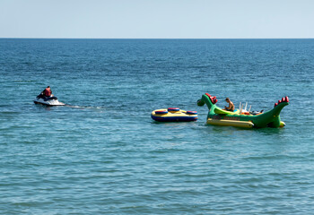 August 24, 2025: Jet ski towing an inflatable banana on the sea in Myskhako, Russia, showing beach entertainment, water sports and summer coastal recreation