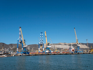 Fototapeta premium August 22 2025 View of Novorossiysk port Russia with cargo ships and cranes on the coastline. Industrial maritime scene on the Black Sea