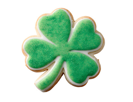 A beautifully decorated green four leaf clover sugar cookie against a solid black background