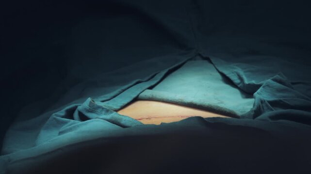 Surgeon cleaning sutured surgical incision with povidone iodine and gauze, post-operative care