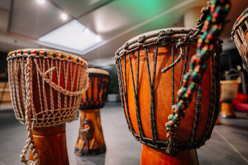 Traditional African drums with intricate beadwork and textured surfaces, arranged in a vibrant music studio, showcasing cultural artistry and craftsmanship in rhythm and sound