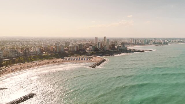Aerial view of Varese beach in Mar del Plata, Argentina, as the camera moves over the ocean towards the shore, capturing the city skyline