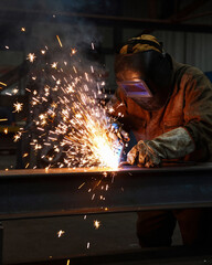 Welder with Sparks Flying in Dark Factory - Industrial Manufacturing