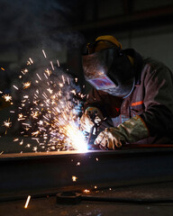 Welder with Sparks Flying in Dark Factory - Industrial Manufacturing