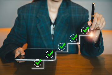 Professional woman using a tablet with digital checklist and check marks, symbolizing productivity and success in a modern office.