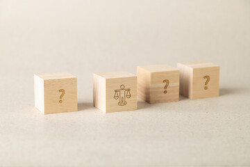 Selective focus on wooden blocks with question marks and a scale icon of a person. Concept for decision making, ethics, legal choices, business dilemma, and moral balance in professional life.