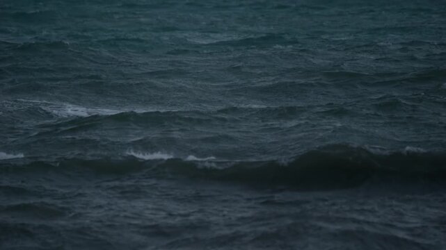 Blue hour recording of rough ocean waves captured in slow motion with heavy wind and pre storm sea conditions.