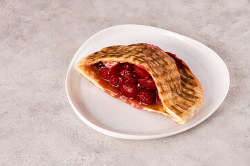 Delicious pastry filled with fresh strawberries and cherries, beautifully presented on a white...