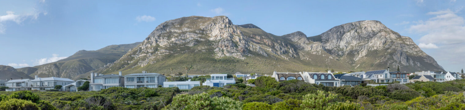 houses on shore green slopes and barren hills at Hermanus Cliff Path, South Africa