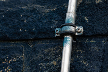 Metal pipe secured to a stone wall in industrial area