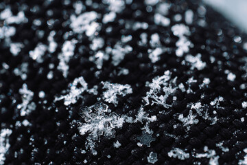 Macro snow crystals on black knitted fabric. High quality photo