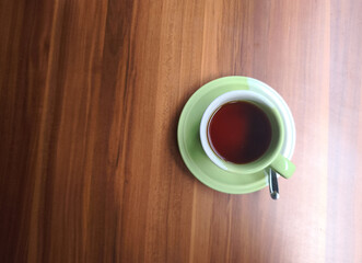 Obraz premium Top View Green Cup of Hot Tea or Coffee on Wooden Table with Copy Space, Minimal Flat Lay Beverage Background