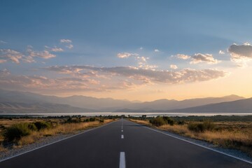 Fototapeta premium Scenic road at sunset with mountain and lake views under a vibrant sky