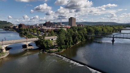 Obraz premium Binghamton, NY downtown city skyline with office buildings, historic architecture, public parks and river flowing through town on Summer sunny warm day